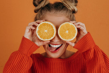 woman holding oranges over her eyes
