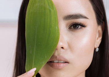 lady holding a leaf in front of her face - sustainable skincare
