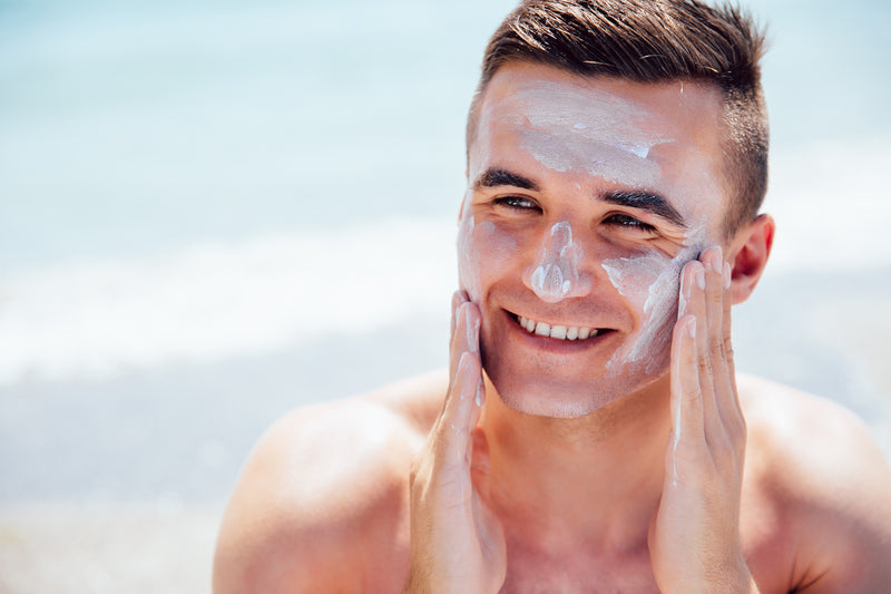Smiling man putting sunscreen on his face