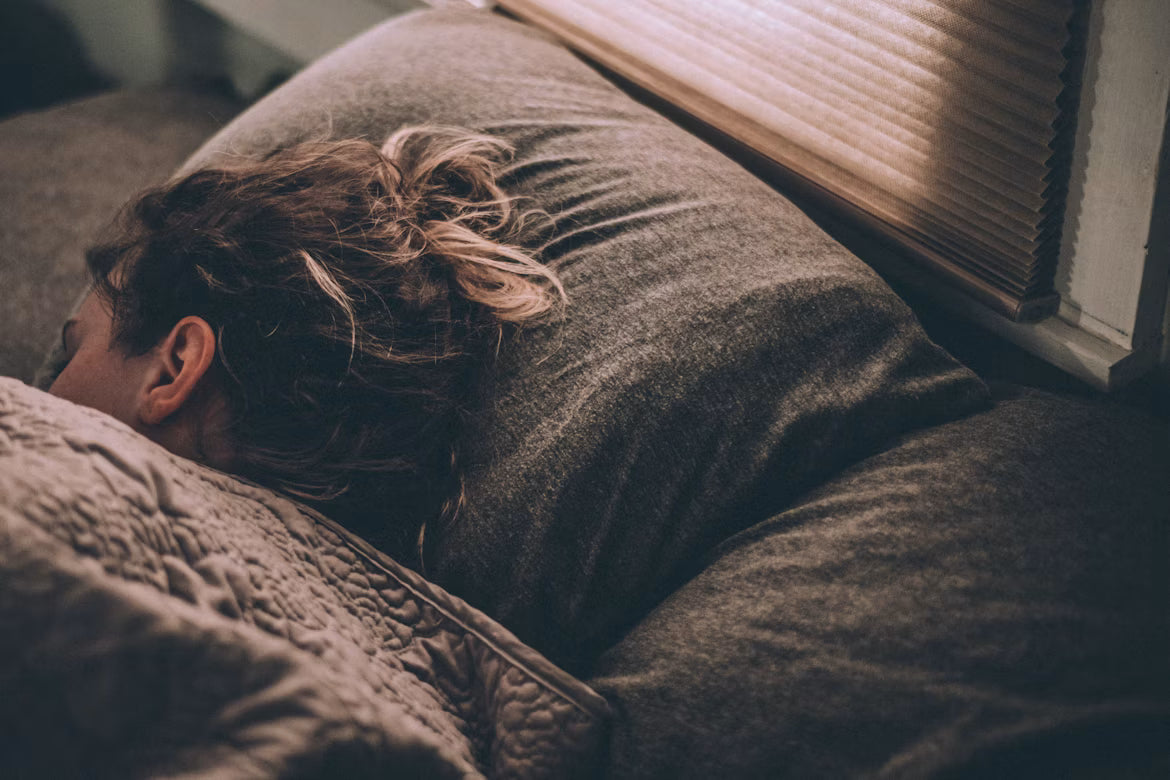 A woman sleeping in bed with a quilt over her.