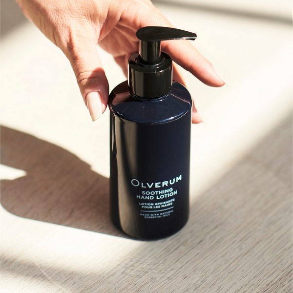 a hand reaching for a bottle of Olverum Soothing Hand Lotion
