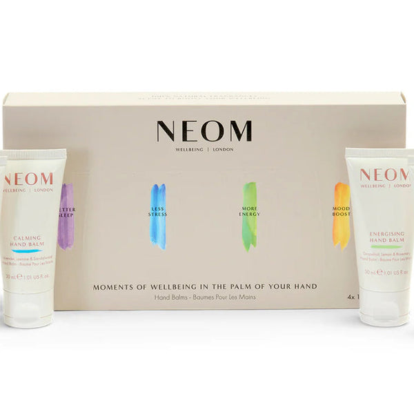 NEOM Moments of Wellbeing in the Palm of Your Hand gift set, featuring a beige presentation box with four small white hand cream tubes arranged in front on a white background.