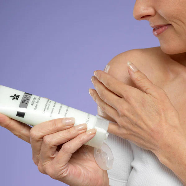 a closeup of a user applying PRAI Beauty Ageless Upper Arm Creme to their shoulder