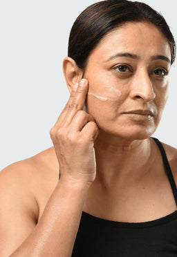a women applying Minimalist Granactive Retinoid 02% to her cheek