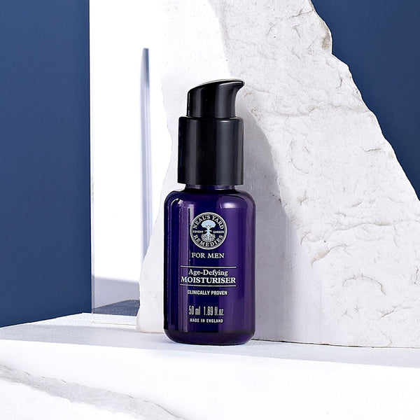 Neal's Yard Remedies Men's Age Defying Moisturiser in front of a chipped stone wall