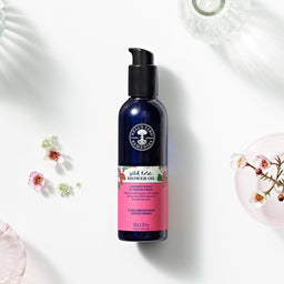 Neal’s Yard Remedies Wild Rose Shower Oil next to a range of small flowers