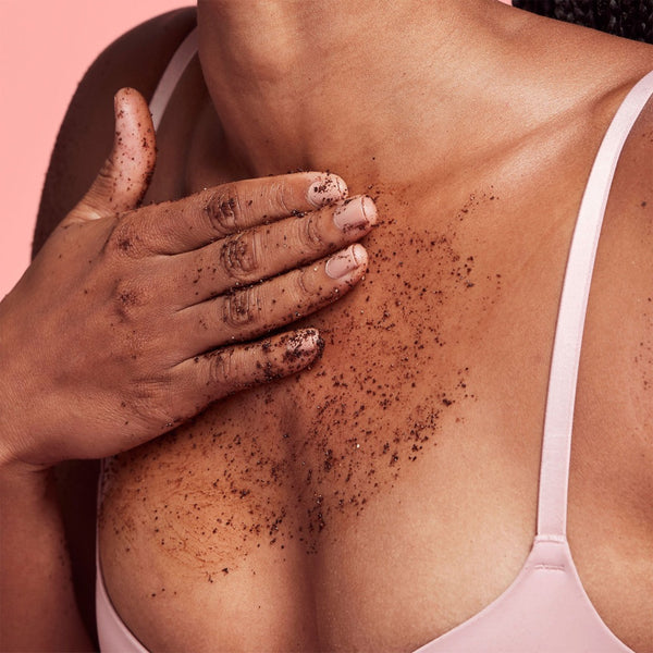 a closeup of a women applying the scrub to her chest
