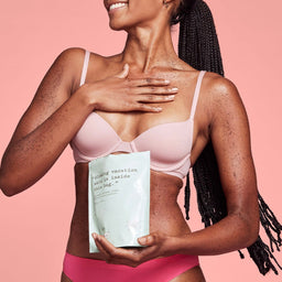 a women holding a bag of Frank Body Coconut Coffee Scrub 200g infront of her chest