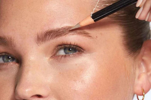 close up of woman applying brow pencil to her eyebrows