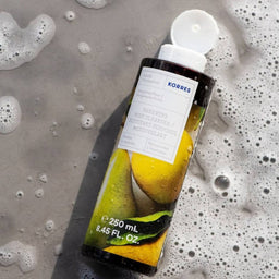 KORRES Bergamot Pear Shower Gel bottle laying on a beach