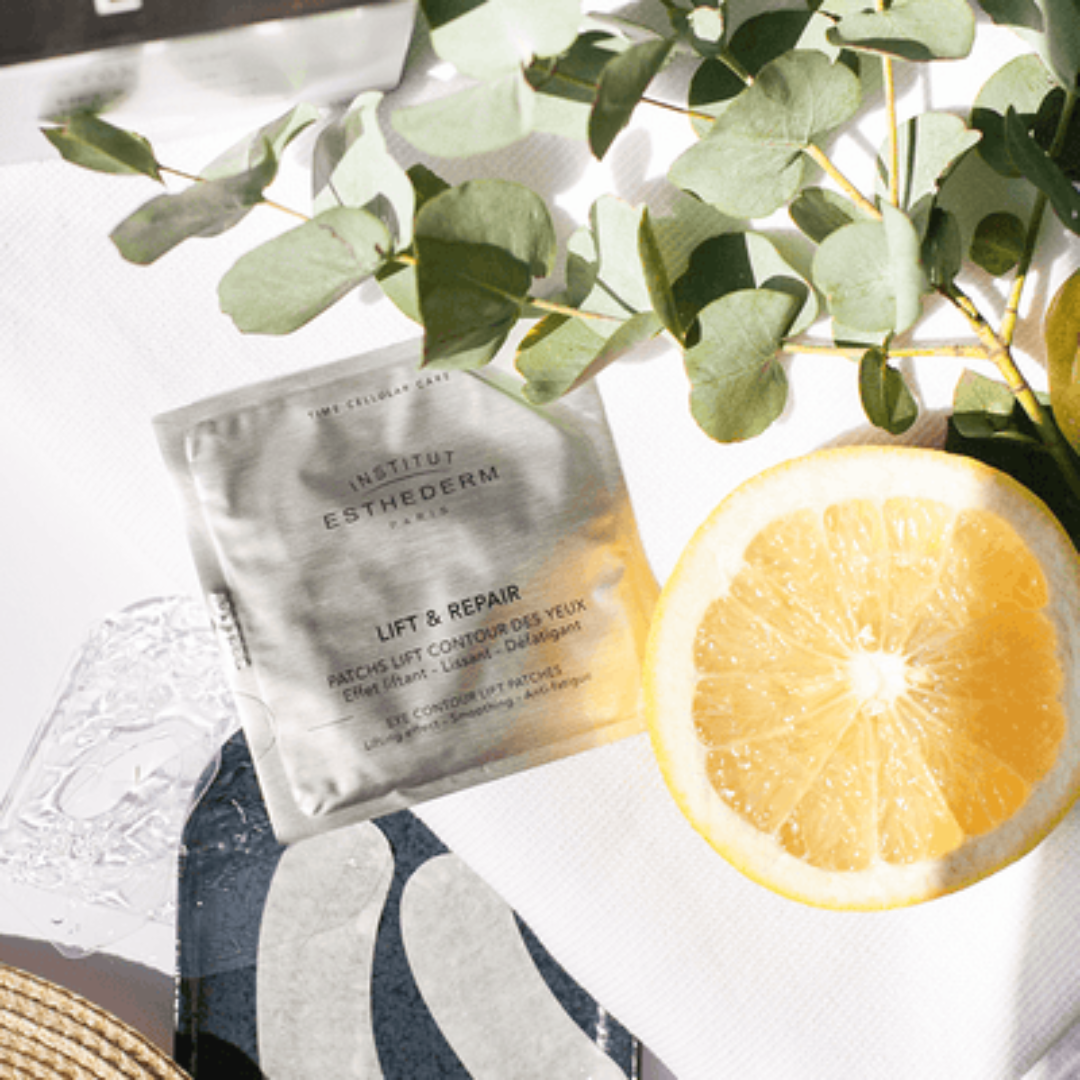 Institut Esthederm Eye Contour Lift Patch on a table top with a slice of lemon laced next to it