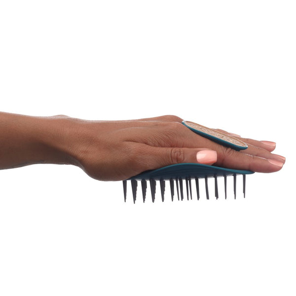 A hand holding a dark teal wide-tooth comb with black bristles against a solid white background.