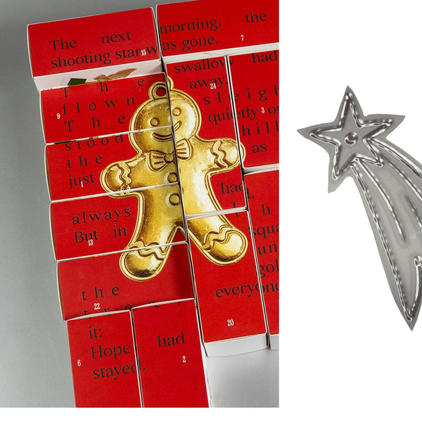 A silver metal shooting star-shaped cookie cutter shown next to a Christmas advent calendar made from red matchboxes with printed text and a gold gingerbread man decoration.
