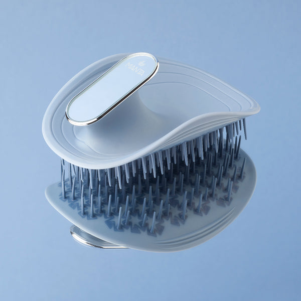 Grooming brush with clear handle and black bristles on a light blue background