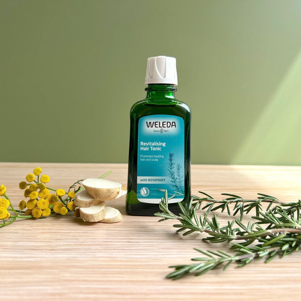 Weleda bottle on a wooden surface with herbs and flowers