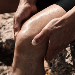 Close-up of a person's knee being massaged outdoors