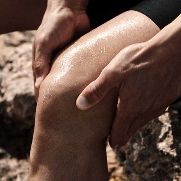Close-up of a person's knee being massaged outdoors