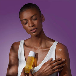 a women holding a bottle of ESPA Restful Bath & Body Oil in front of her chest