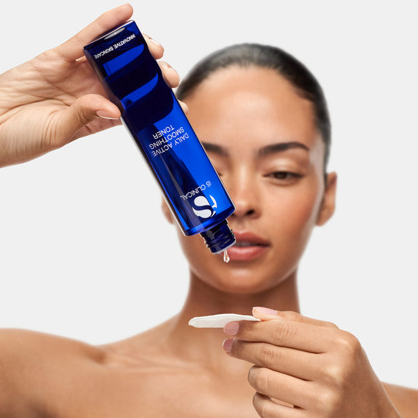A woman holding a blue bottle of Shiseido Ultimainline Hairline Hair Building Fibro Solution and applying a drop to a swab.