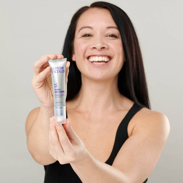 a woman holding a tube of Super Facialist Retinol+ Anti-Ageing Serum to the camera