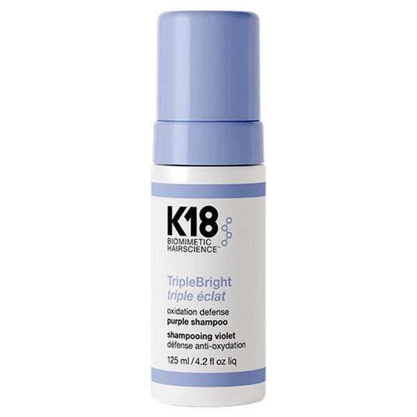 K18 TripleBright Purple Shampoo in a white bottle with a lavender-blue cap and matching blue text accents, on a plain white background.
