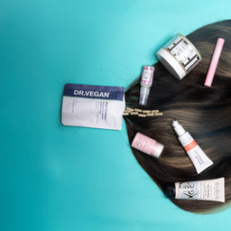 Hair care products on a teal background with a wig