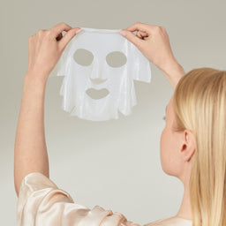 a model holding a mask to the air