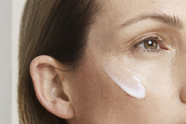 a close up of a women with cleanse applied to her cheek
