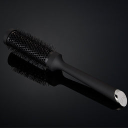 Black hairbrush on a reflective black surface
