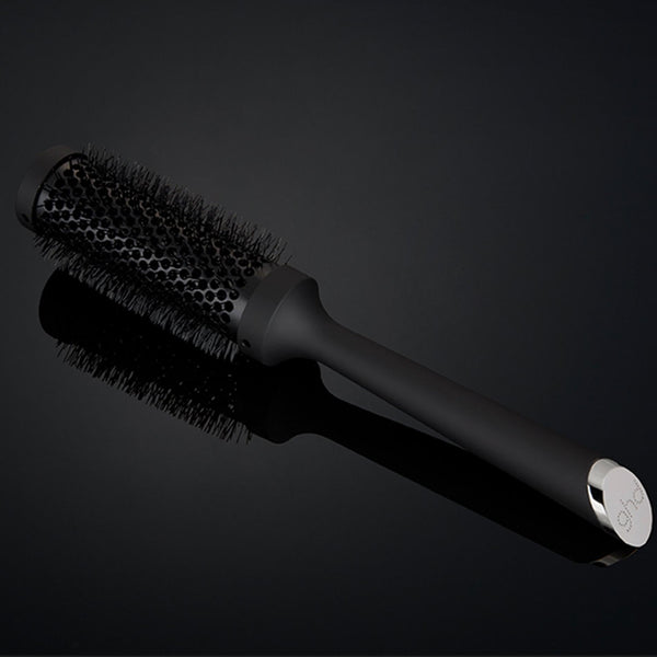 Black hairbrush on a reflective black surface