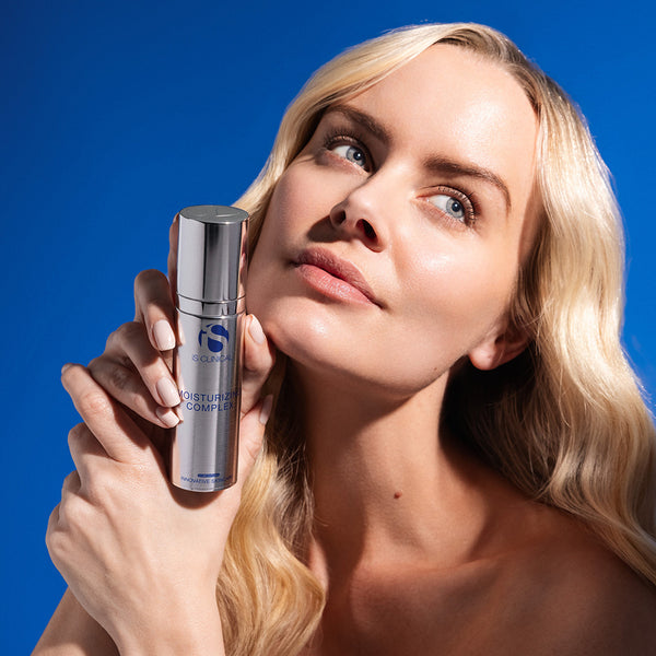 Woman holding a skincare product against a blue background