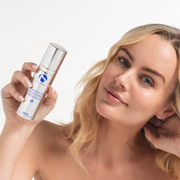 Woman holding a skincare product with a plain background