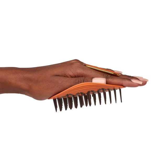 Hand holding an orange hairbrush with black bristles on a white background