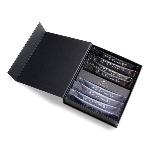 An open black presentation box containing several slim dark packets with visible 'ANCIENT BRAVE' text, photographed on a clean white background.