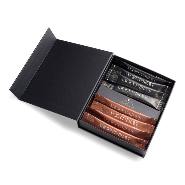 An open black presentation box on a white background, containing several slim packets. The packets are arranged in two rows: the top row is black with gold lettering reading 'ANCIENT BRAVE', and the bottom row is metallic bronze/copper with matching lettering.