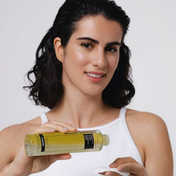Woman holding a bottle of skincare product against a white background