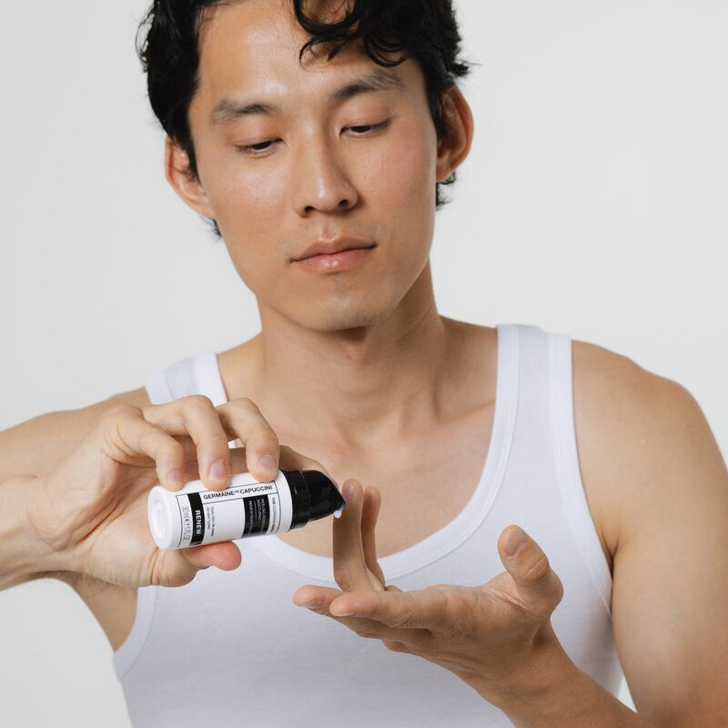 Man applying a skincare product to his hand against a white background