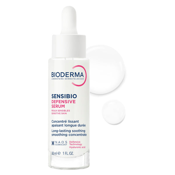 Bioderma Sensibio Defensive Serum in a clear glass dropper bottle with a white cap, shown on a white background with two floating droplets behind it.
