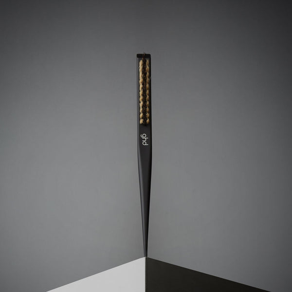 Black hairbrush with gold bristles on a gray background