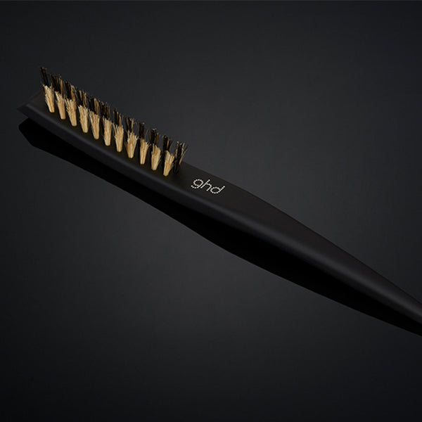 Black hair straightening brush with gold accents on a dark background
