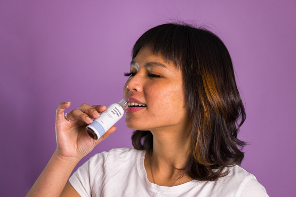 a woman drinking a bottle of Proto-col Collagen Shot Red Berry