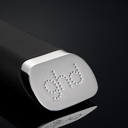 Close-up of a ghd hair styling tool on a black background