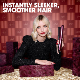 Woman holding a ghd hair straightener with text 'Instantly Sleeker, Smoother Hair' on a patterned background.