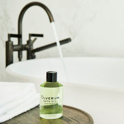 a bottle of Olverum Bath Oil next to a bath