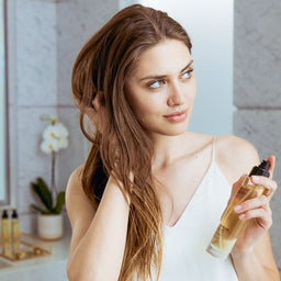 a women holding a bottle of Olverum The Dry Body Oil