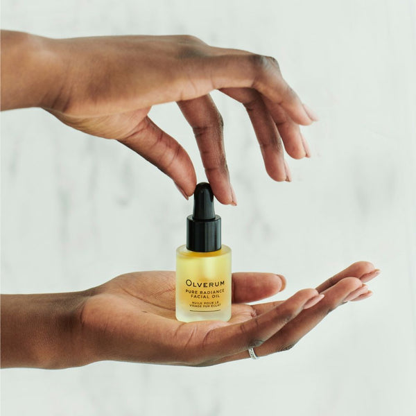 Olverum Facial Oil held in the palm of a hand