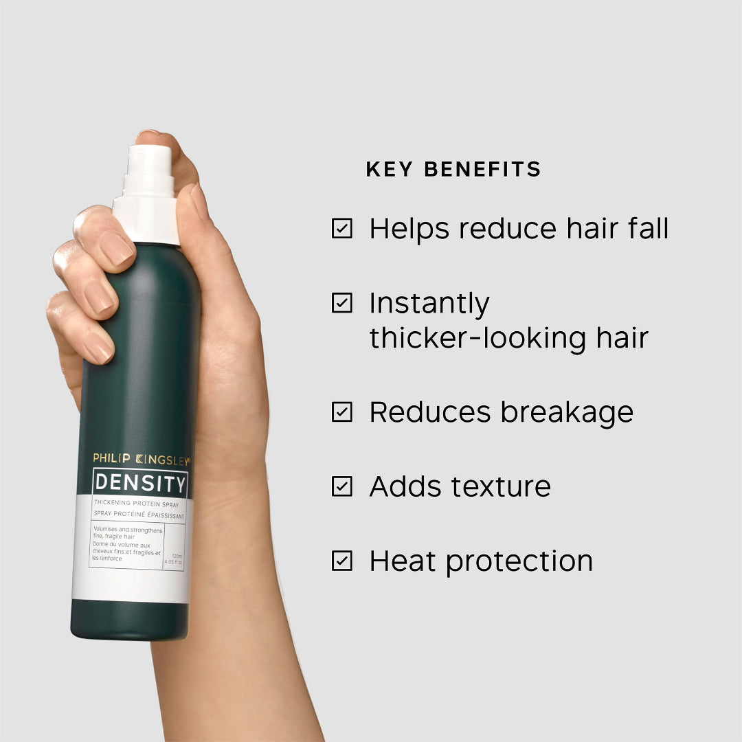 Hand holding a bottle of Philip Kingsley Density product with key benefits listed on a gray background