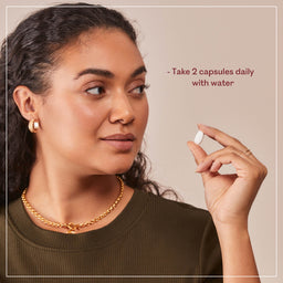 Woman holding a supplement capsule with text on a beige background