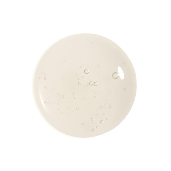 A circular swatch of translucent, slightly glossy cream-colored gel or liquid with small air bubbles, centered on a solid white background.