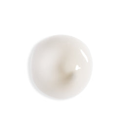 A glossy, smooth, off-white circular droplet or gel pool on a solid white background.